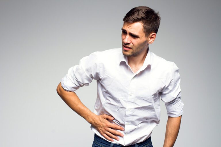 Homem com mão na barriga e sentindo dores.